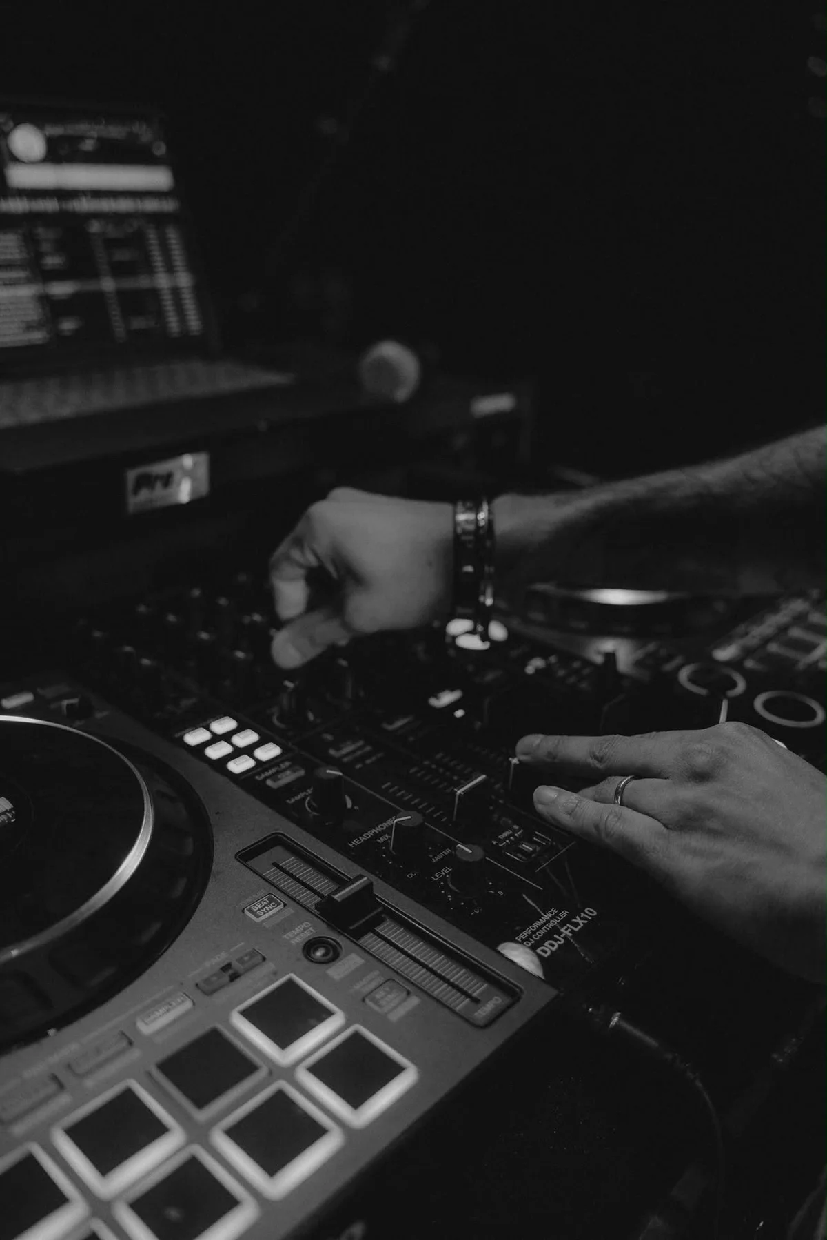 Black-and-white close-up of hands on the DJ controller