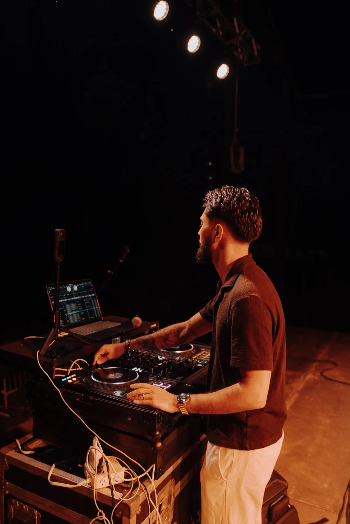 DJ Sarif mixing at the decks under warm stage lighting